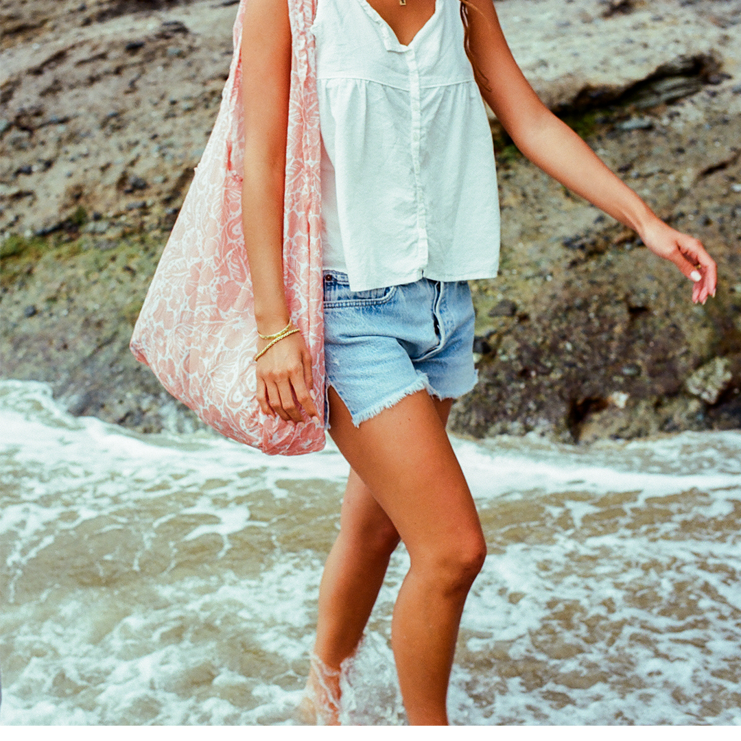 Woman walking through a stream with a Packable Tote Bag - Coral Crush - Thread®